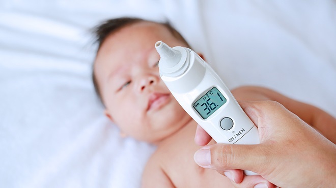 person using ear thermometer to test babies temp